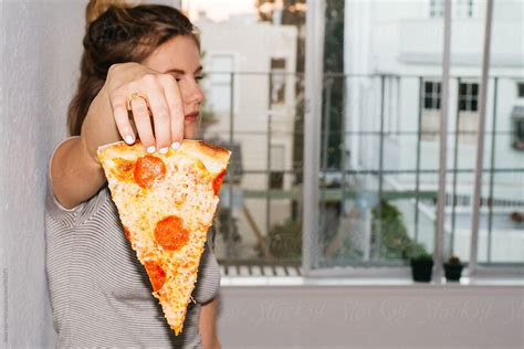 Young Female Holding Slice Of Pizza In Front Of Face By Stocksy Contributor Jesse Morrow