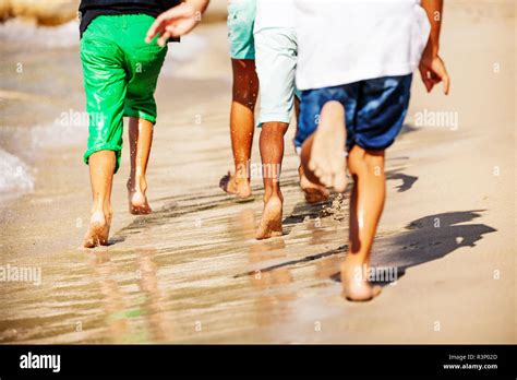 Kids running barefoot on sandy beach in summer Stock Photo - Alamy