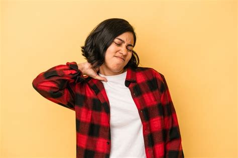 Jovem mulher latina isolada em fundo amarelo sofrendo de dor no pescoço devido ao estilo de