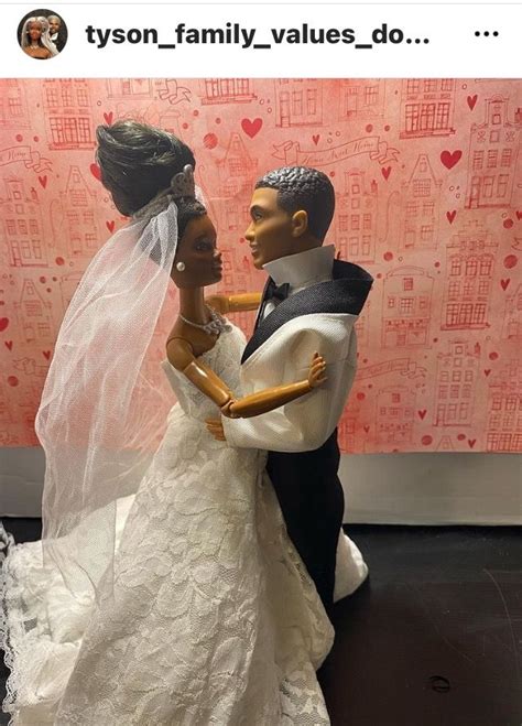 A Bride And Groom Figurine On Display In Front Of A Wall With Hearts