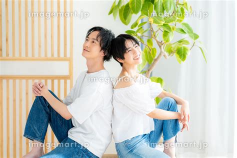 背中合わせで寄り添って座る若い日本人カップル （男女 / 人物）の写真素材 [243014233] - イメージマート