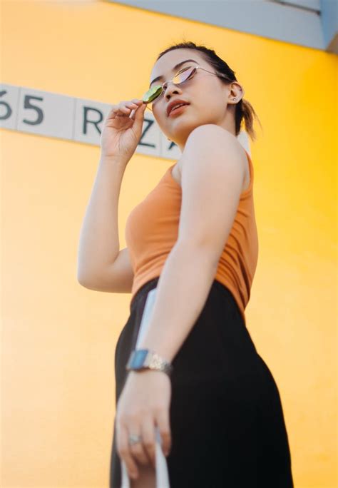 Low Angle Photo Of Woman In Sunglasses Orange Top And Black Bottoms