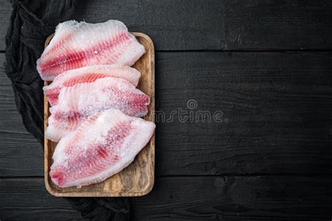 Filete De Pescado Congelado Sobre La Mesa De Madera Negra Vista