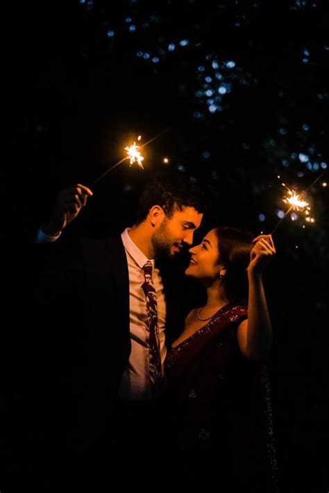 A Man And Woman Holding Sparklers In Their Hands