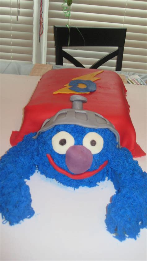 a cake shaped like sesame street characters is on a table with a chair ...