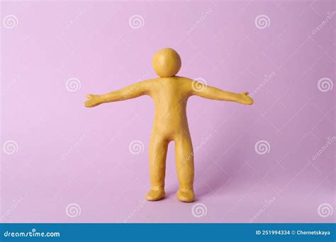 Human Figure With Arms Wide Open Made Of Yellow Plasticine On Violet