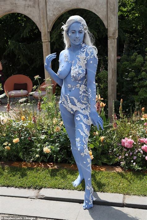 A Woman With Blue Paint On Her Body Is Standing In Front Of Flowers And