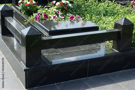 part of a black marble fence on a gray stone tile at the grave in the ...