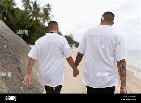 Backs Of A Gay Couple Walking Along The Beach Holding Hands Stock Photo Alamy
