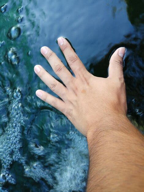 Premium Photo Close Up Of Hand Touching Water Surface In River