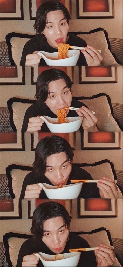 The Man Is Eating Noodles With Chopsticks In Front Of His Face While