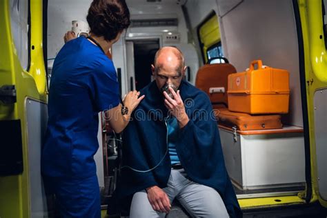 Nurse Stands With Man Who Sits In Oxygen Mask In Blanket In The