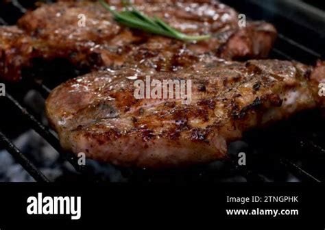 Grilling Juicy Pork Steak On Heat Of Barbecue Grid And Watering With