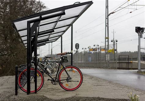 a bike parked next to a bus stop on the side of a road in the rain