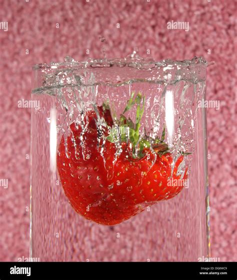 Strawberry Dropped In A Glass Of Water Creating A Splash Stock Photo