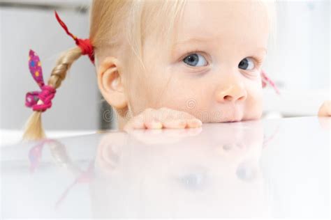 A Blonde Girl With Perky Pigtails Looks Sweetly Into The Camera And Looks Out From Behind The