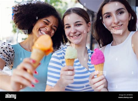 Three Cheerful Multiracial Female Teenager Girls Holding Colorful Ice Cream Outdoors On Street