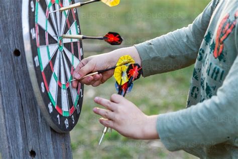 Image of Young boy pulling throwing darts of game board - Austockphoto