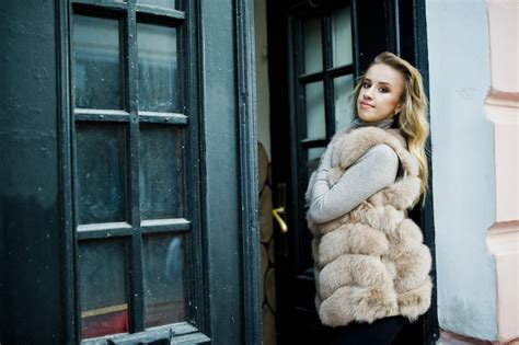Fille blonde au manteau de fourrure posé contre la vieille porte en bois Photo Premium