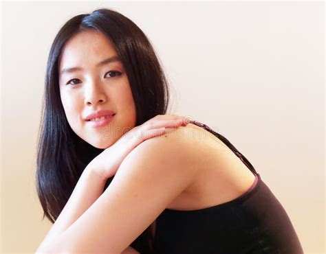 With A Faint Smile And Arm On Bare Shoulder Young Woman Looks To Camera