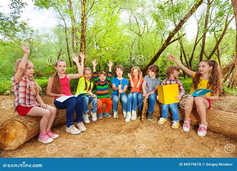 cute kids reading books outdoor sitting   log stock photo image