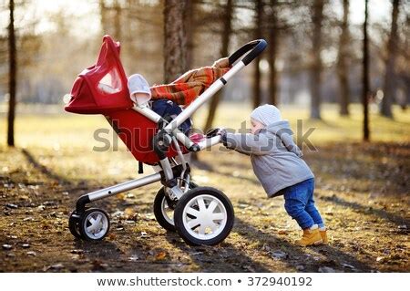 Beautiful toddler boy playing with his stroller walking outdoors at the ...