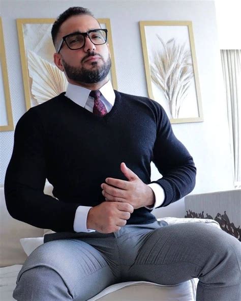 A Man Wearing Glasses And A Sweater Is Sitting On A Couch With His