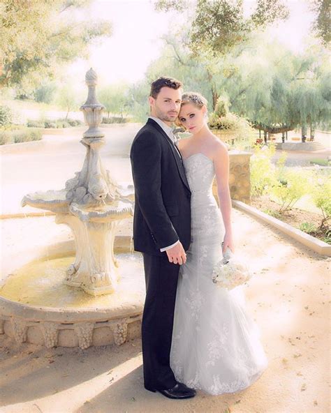 A Bride And Groom Pose For A Photo In Front Of A Fountain At Their Wedding