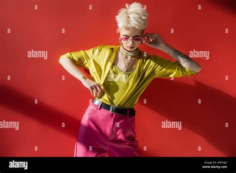 Blonde Albino Woman With Tattoo Adjusting Sunglasses On Carmine Pink Background Stock Photo Alamy
