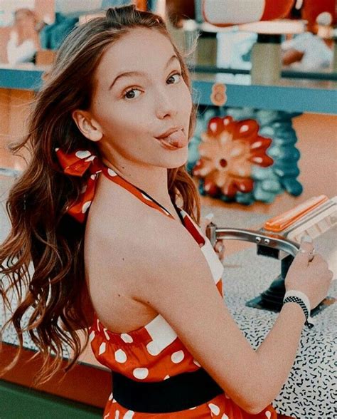 A Woman In An Orange And White Polka Dot Dress Holding A Book While