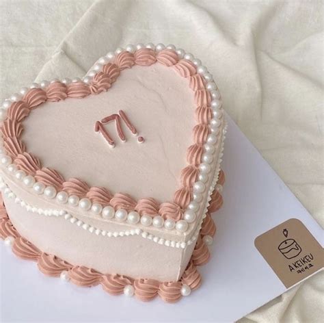 A Heart Shaped Cake With Pearls And Pink Icing On A White Tablecloth