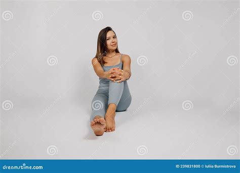 Woman Poses In Studio Beautiful Brunette In Gray Suit For Fitness Or Yoga Is Sitting On Floor