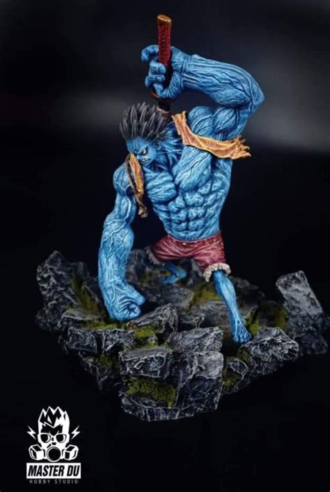 a blue man holding a stick on top of a rock