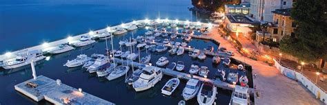 Many Boats Are Docked In The Water At Night Near Some Buildings And