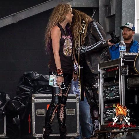 A Man And Woman Standing Next To Each Other In Front Of A Stage With