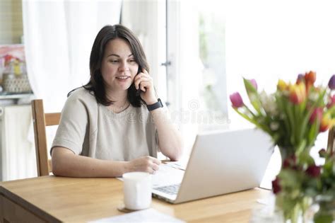 Beautiful Brunette Girl Smiling Sitting At Table In Front Of Laptop And Documents Talking On