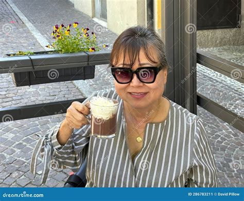Sixty Five Year Old Female Korean Tourist Enjoying A Cup Of Hot Chocolate With Whipped Cream In