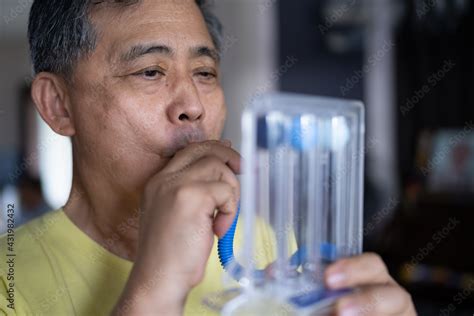 Old Man Uses A Tri Ball Incentive Spirometer For Check His Lung