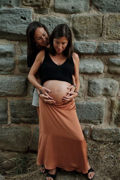 Vertical Closeup Of A Pregnant Lesbian Couple Doing A Photoshoot In A