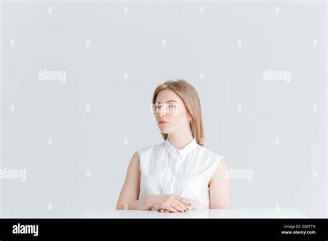 Attractive Blonde Woman Sitting At The Table Isolated On A White Background And Looking Away