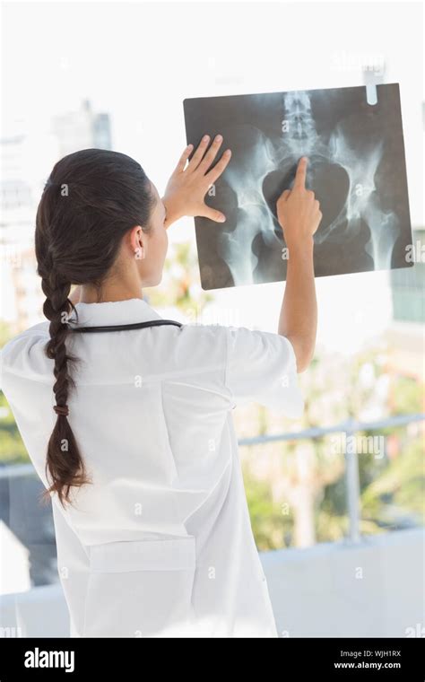 Rear View Of A Female Doctor Examining X Ray In The Medical Office