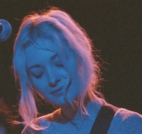 Blonde Woman Playing Guitar And Singing Into Microphone
