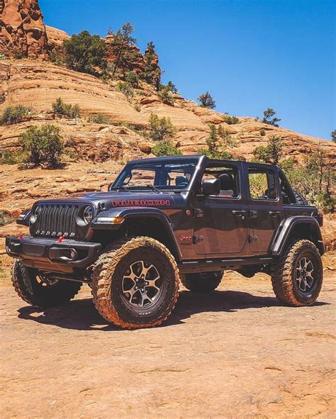 A Black Jeep Parked On Top Of A Dirt Road Next To A Rocky Mountain Side