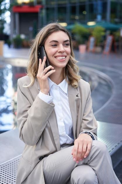 Foto vertical de uma mulher sorridente falando no celular enquanto está