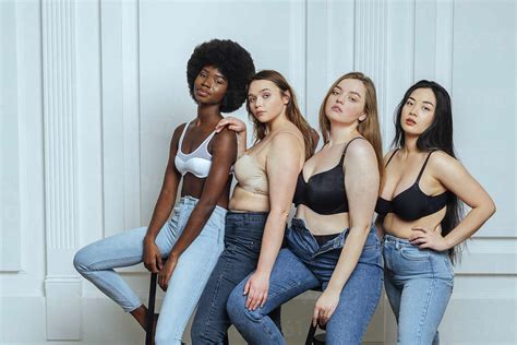 Multi Ethnic Group Of Women Wearing Bras And Jeans Against Wall Stock Photo