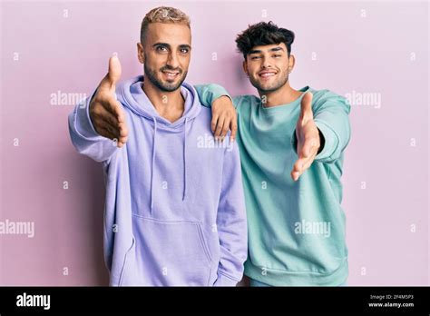 Homosexual Gay Couple Standing Together Wearing Casual Clothes Smiling Friendly Offering