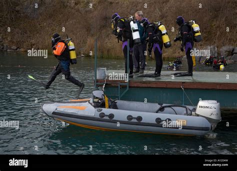 Scuba Diver Jumping Into Water With Other Divers Waiting On The Jetty