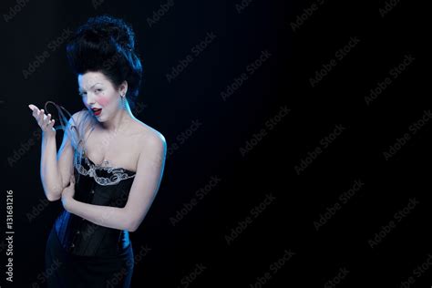 Actress Brunette Woman With High Hair In Corset Decorated With Feathers In Antique Style On A