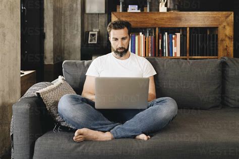 Mature Man Sitting On Couch Using Laptop Stock Photo