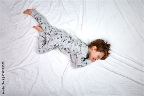 From above a boy is seen sleeping on a white bed in pajamas. Calm ...